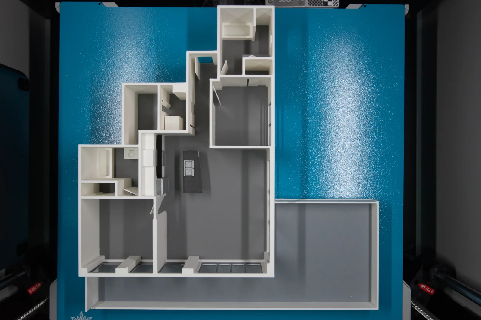 Top-down view of a 3D printed floor plan model of an apartment with a large balcony